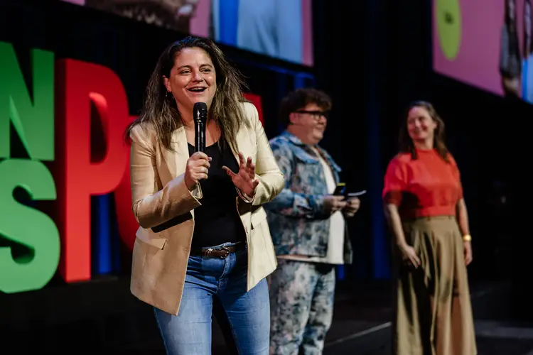 Foto van een enthousiaste Barbara die in een microfoon praat tijdens een GroenLinks-PvdA congres.